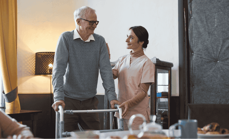 Power of Companionship in Senior Care - Young caregiver woman is helping senior man to move