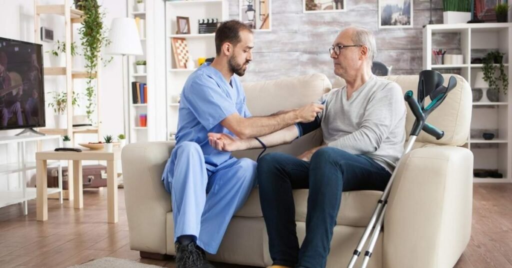 Male nurse providing quality home health care support and checking blood pressure of an elderly man sitting on a sofa at home