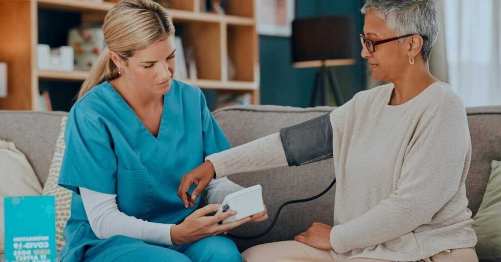 Home caregiver checking a senior woman’s blood pressure during a home visit, illustrating support available when families apply for NJ PCA services.