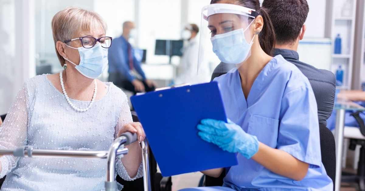 Home health aide assisting an elderly woman with a walker while reviewing care notes, illustrating PCA service vs private duty nursing in New Jersey home health care.